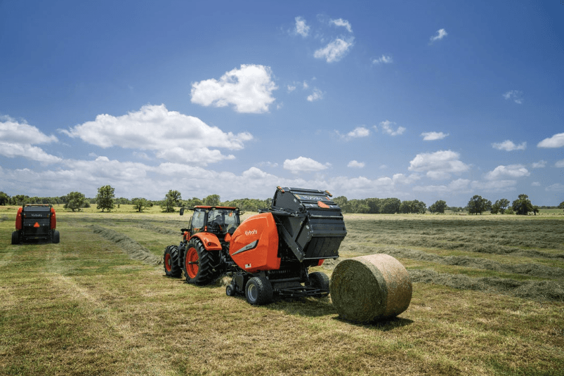 Tractor in a field with baler attachment making bales