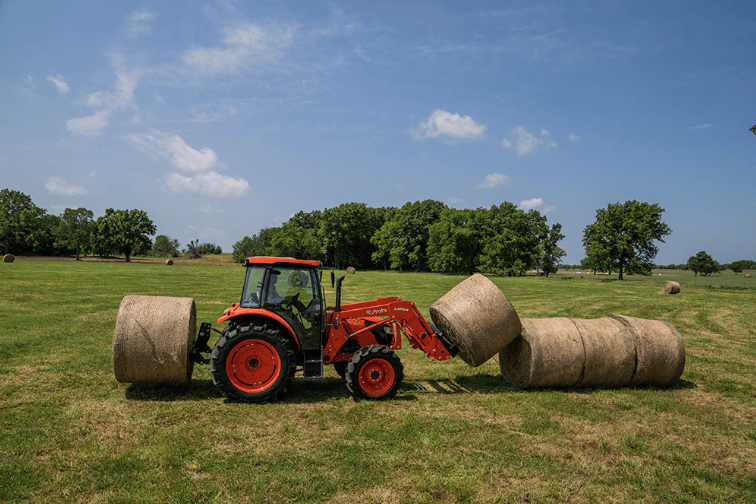 Tractor moving hay bales