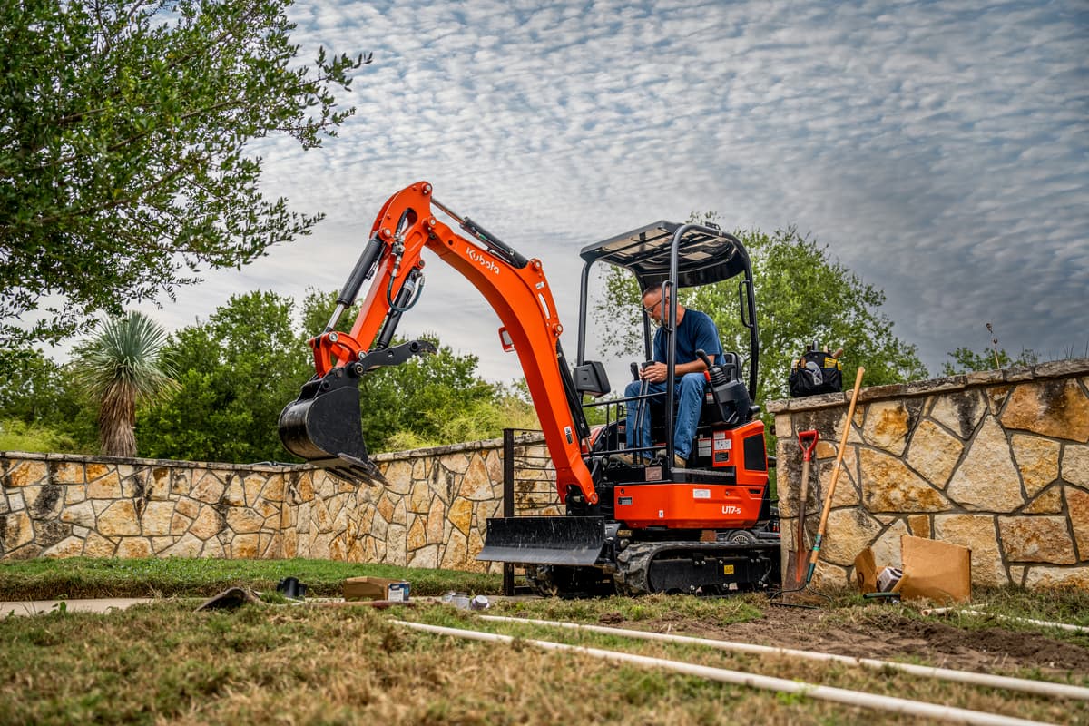 Kubota U17 fitting through the gate in a stone fence