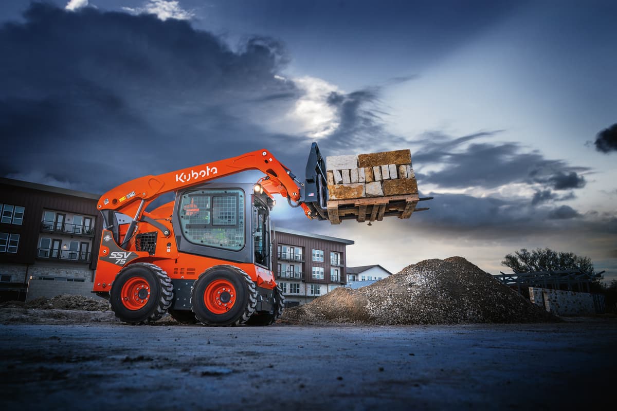 Kubota SSV75 lifting a pallet of concrete blocks